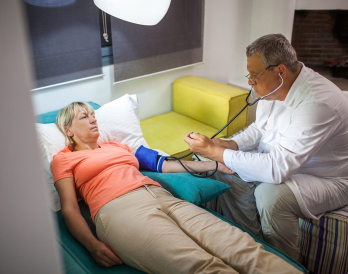 Doctor measuring blood pressure of woman at home